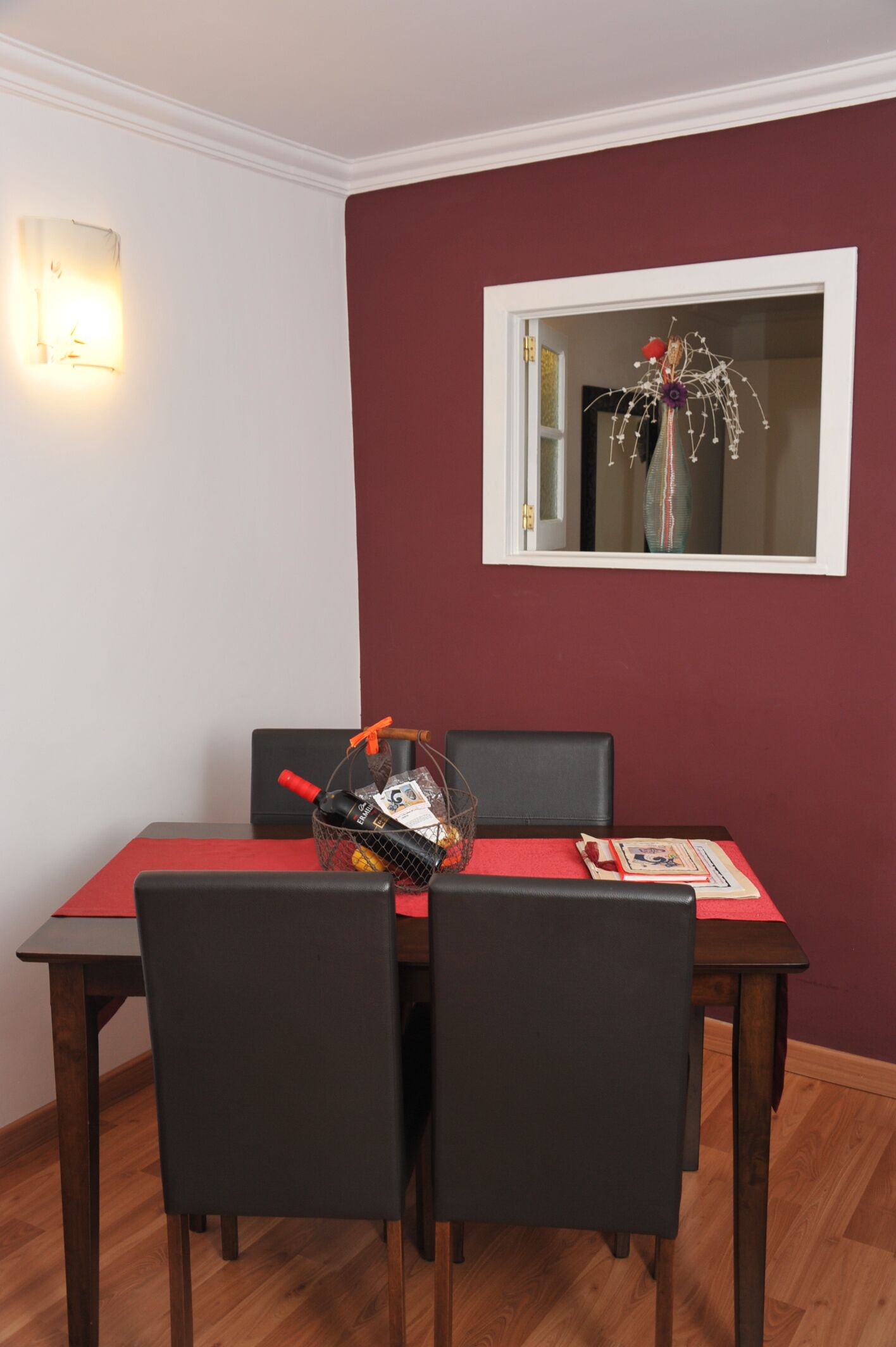 Zona pranzo con tavolo apparecchiato per quattro persone, runner rosso sul tavolo e un oggetto decorativo.