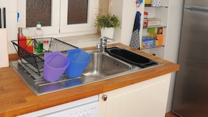 Een keuken met een vaatwasser, een spoelbak en een raam erboven.
