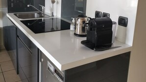 Une cuisine moderne équipée d’un lave-vaisselle encastré, d’une bouilloire, d’une machine à café et d’un évier.