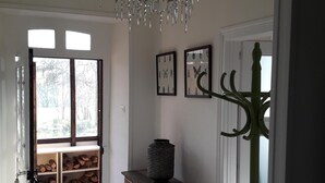 Un pasillo con un banco de madera, un jarrón decorativo y cuadros de insectos en la pared.