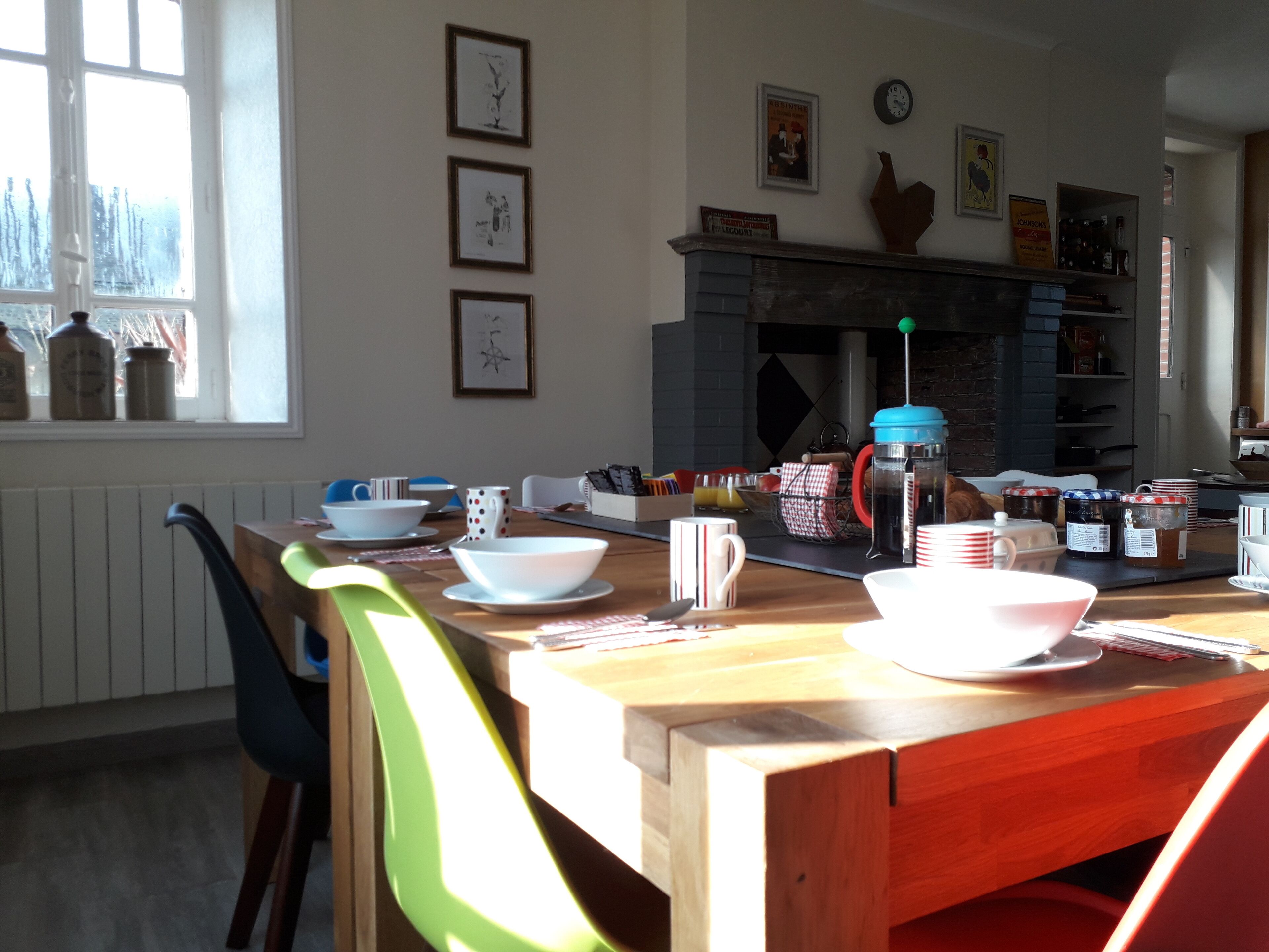 A dining area with a wooden table, chairs, and various kitchen items.