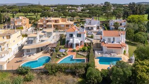 Zona residencial con varias casas, una piscina y un césped bien cuidado.
