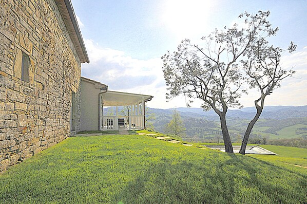 A stone building with a covered porch and a view of rolling hills. - Lovely Villa on Tuscan/Umbria border; Private 18m pool; Glorious Views. (Lippiano)