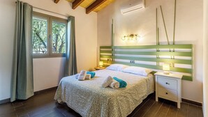 Ein Schlafzimmer mit einem Bett, Nachttischen, einer Klimaanlage und einem Fenster mit Vorhängen.