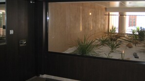 Et værelse med et stort vindue, en trædør og en lille indendørs have med planter og sten.