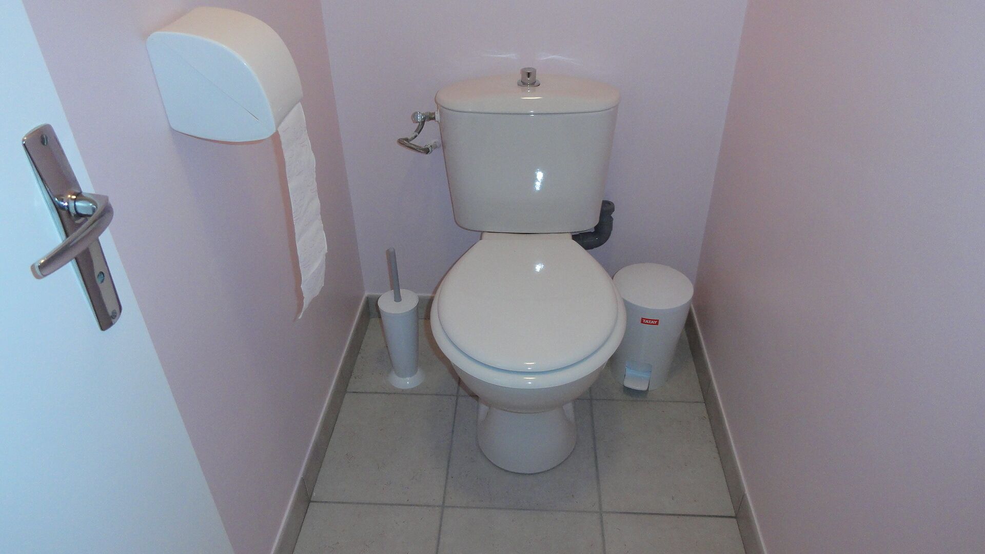 A bathroom with a toilet, a toilet paper holder, and a trash can.