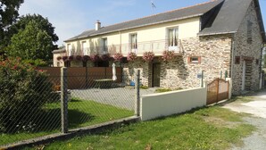A stone building with a sloped roof, a fenced yard, and a small garden area. - 7 km from DERVAL, stone house 4/5 adults + 1 baby. INTERNET BOX. (Conquereuil)
