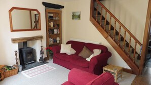 A living room with a red sofa, a fireplace, a wooden staircase, and a bookshelf.