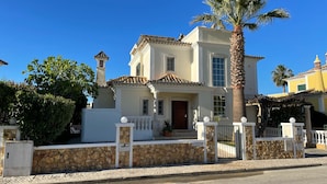 Una casa de dos pisos con fachada de piedra, techo de tejas y una palmera al frente.