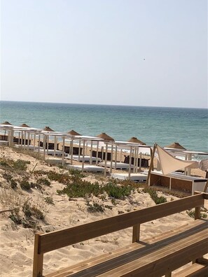 A beach with wooden benches and thatched umbrellas. - Algarve, Almancil: Fully secluded villa with private pool urb. Varandas do Lago. (Almancil)