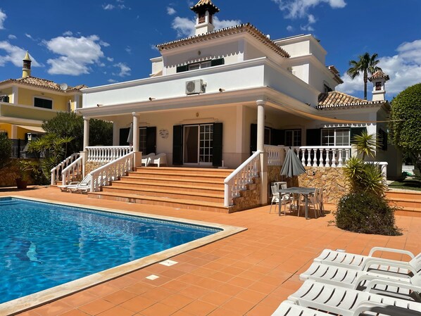 A two-story house with a swimming pool, outdoor seating, and a staircase leading to the entrance. - Algarve, Almancil: Fully secluded villa with private pool urb. Varandas do Lago. (Almancil)