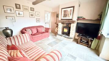 Una sala de estar con chimenea, un sofá, un televisor y cuadros en la pared.