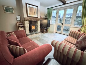 A living room with a stone fireplace, a television, and a sofa. - 4 Star Cotswold Stone Cottage (Winchcombe)