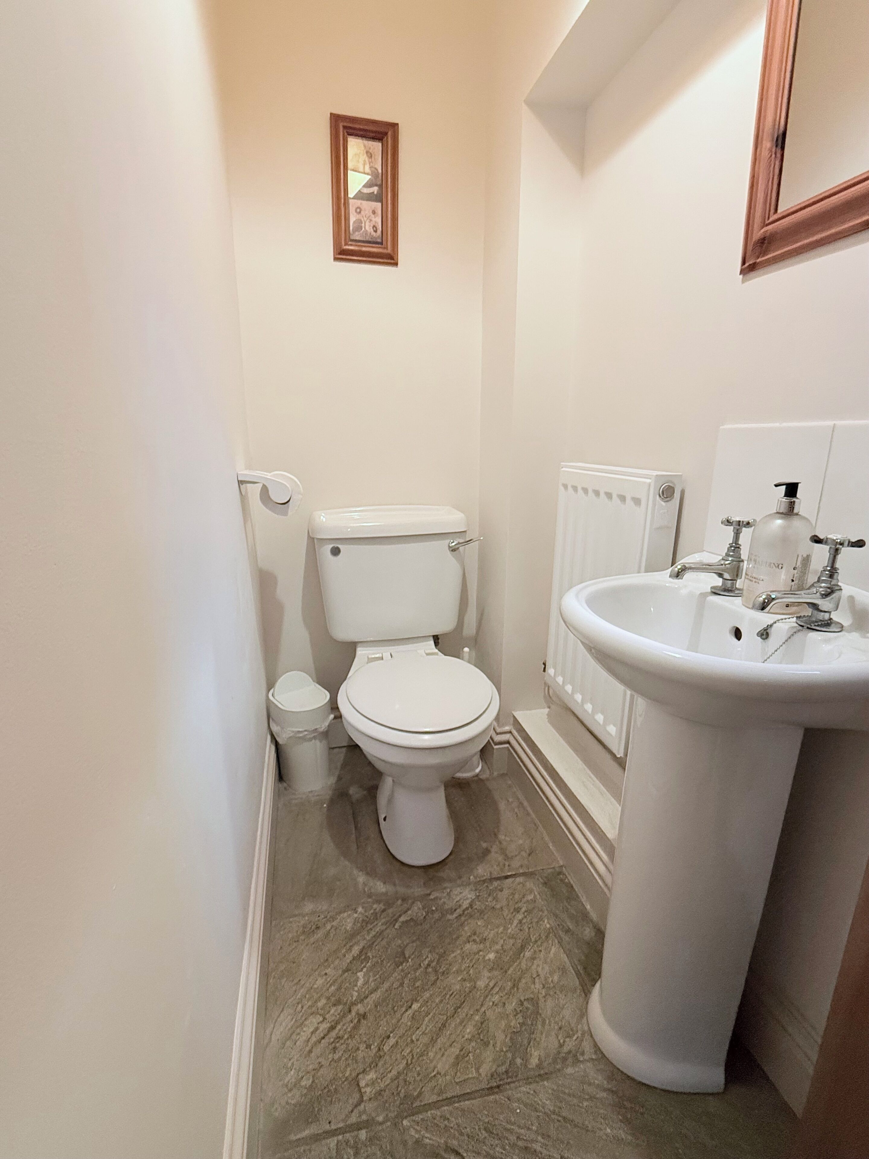 Une petite salle de bain avec des toilettes, un lavabo et un tableau encadré au mur.