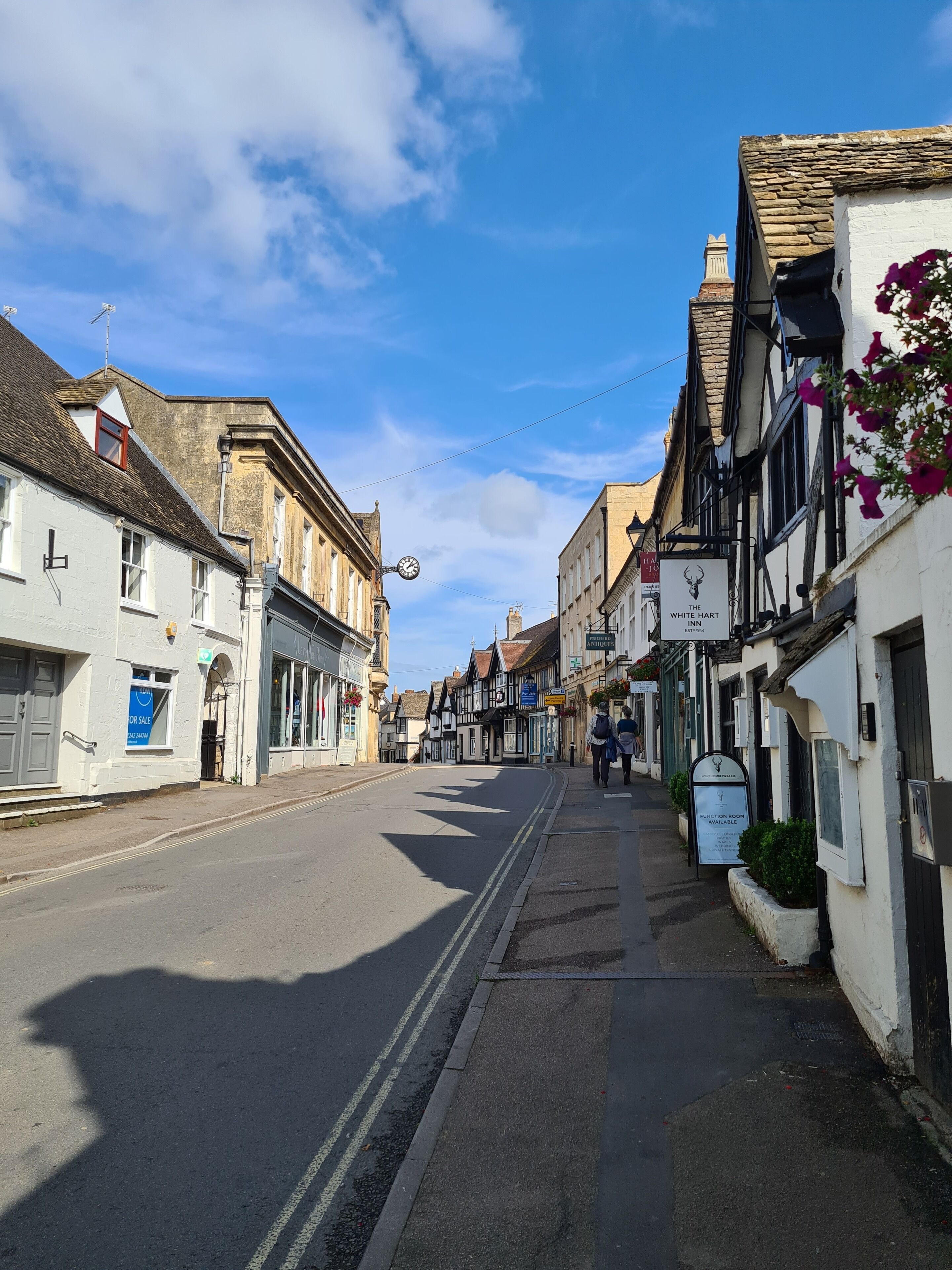 Une vue de rue avec un bâtiment portant l’inscription « The White Hart Inn » et un panneau indiquant « Salle de réception ».