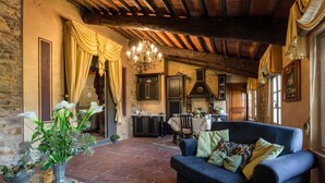 Un salón acogedor con un sofá azul oscuro, una pared de piedra y una cocina rústica al fondo.