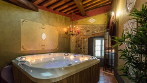 Un cuarto de spa con un jacuzzi, paredes de madera, una chimenea de piedra y un candelabro.