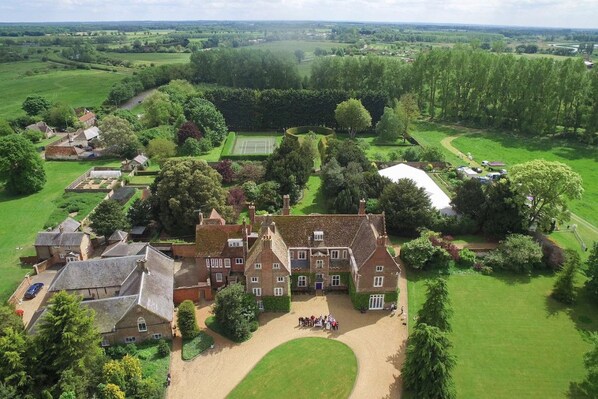 An estate with multiple buildings, a tennis court, and a well-maintained lawn.