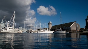 A marina with multiple boats docked, a lighthouse, and a large building with a sloped roof. - A comfortable well located property in Falmouth with generous parking (Falmouth)