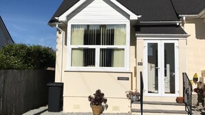 A two-story house with a white facade, a large window, and a door with glass panels. - A comfortable well located property in Falmouth with generous parking (Falmouth)