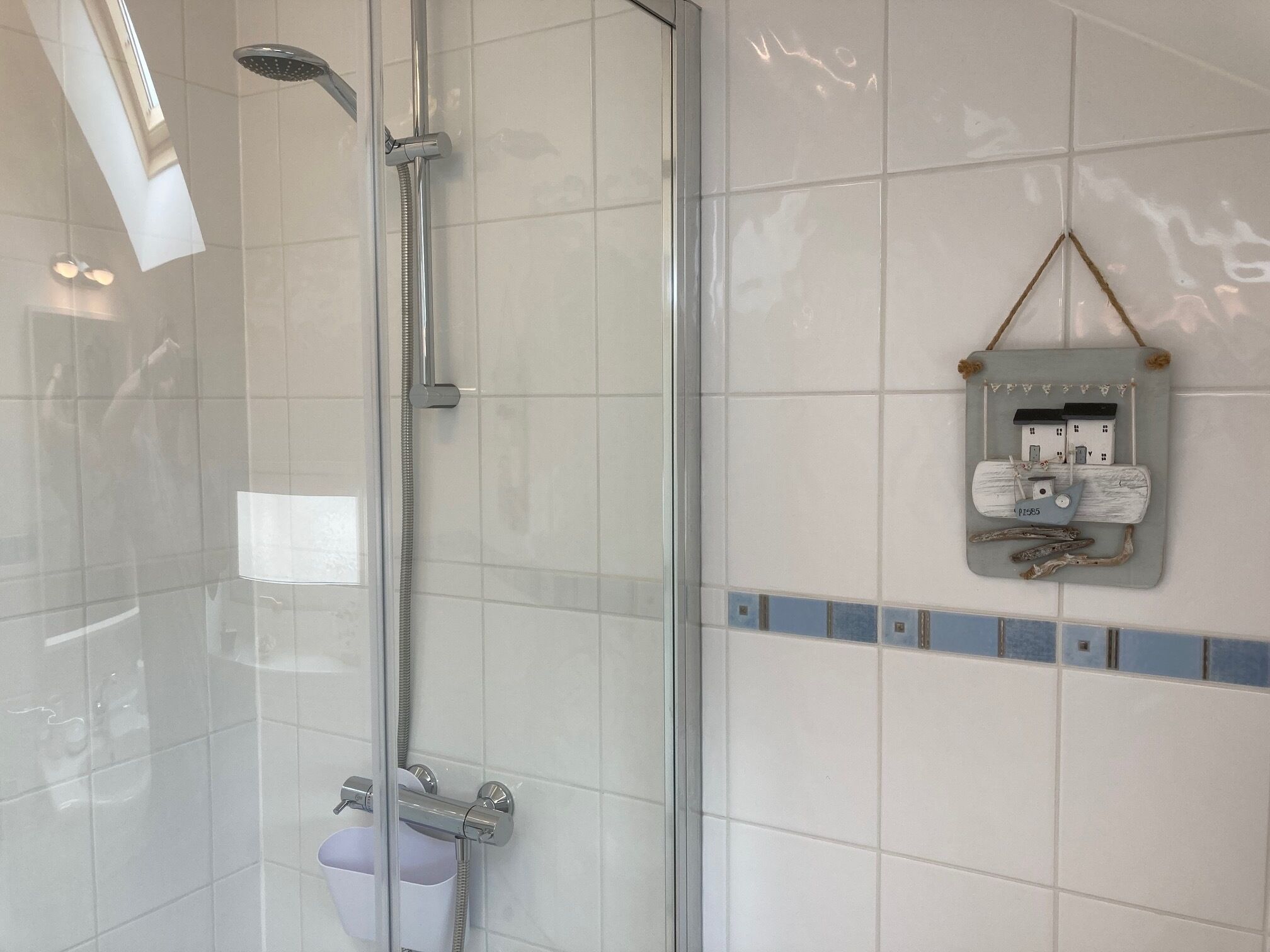 A shower with a glass door, a handheld showerhead, and a wall-mounted control panel.