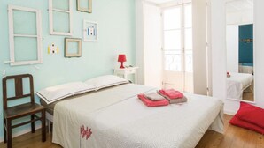 A bedroom with a bed, a chair, a nightstand, and a window. - Castle / Alfama in the historic center (Lisboa)