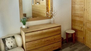 A wooden dresser with a mirror, a small stool, and a framed picture on a carpeted floor. - 2 bedroom apt, balcony facing Mont Blanc, very close to village & GM ski lift (Chamonix-Mont-Blanc)