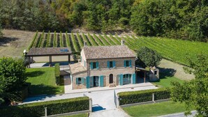 A stone house with a tiled roof, surrounded by a well-maintained garden and vineyard. - Casale Vigneto - 3 bedrooms, pool, AC, wifi, pets, Marche (Mogliano)