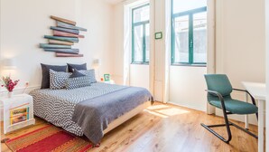 Ein Schlafzimmer mit Bett, Stuhl, Schreibtisch und Fenster.