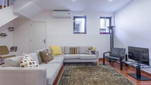 Ein stilvolles Wohnzimmer mit einer Couch, einem Sessel, einem Fernseher und einem gemusterten Teppich.