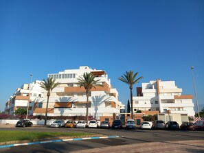 A multi-story residential building with a parking area in front.