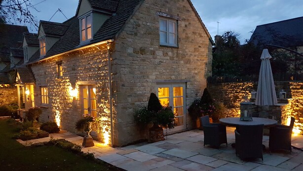 Una casa de piedra con un patio que tiene asientos exteriores y una mesa.
