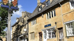 Un edificio de piedra tradicional con un letrero que indica 'Chipping Campden' y un pub llamado 'The White Horse'.
