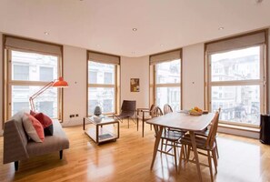 A spacious room with a dining table, chairs, a sofa, and a standing lamp.