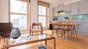 Un appartement moderne doté d’un coin repas, d’une cuisine et de grandes fenêtres.