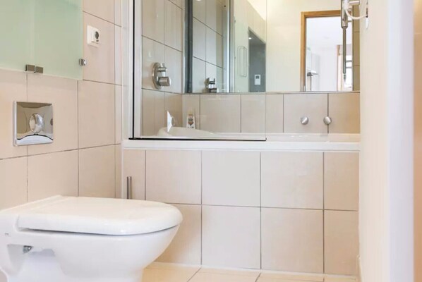 A modern bathroom with a toilet, a sink, and a mirror.