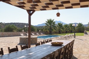 Une terrasse extérieure avec une piscine, des chaises longues et une table à manger.