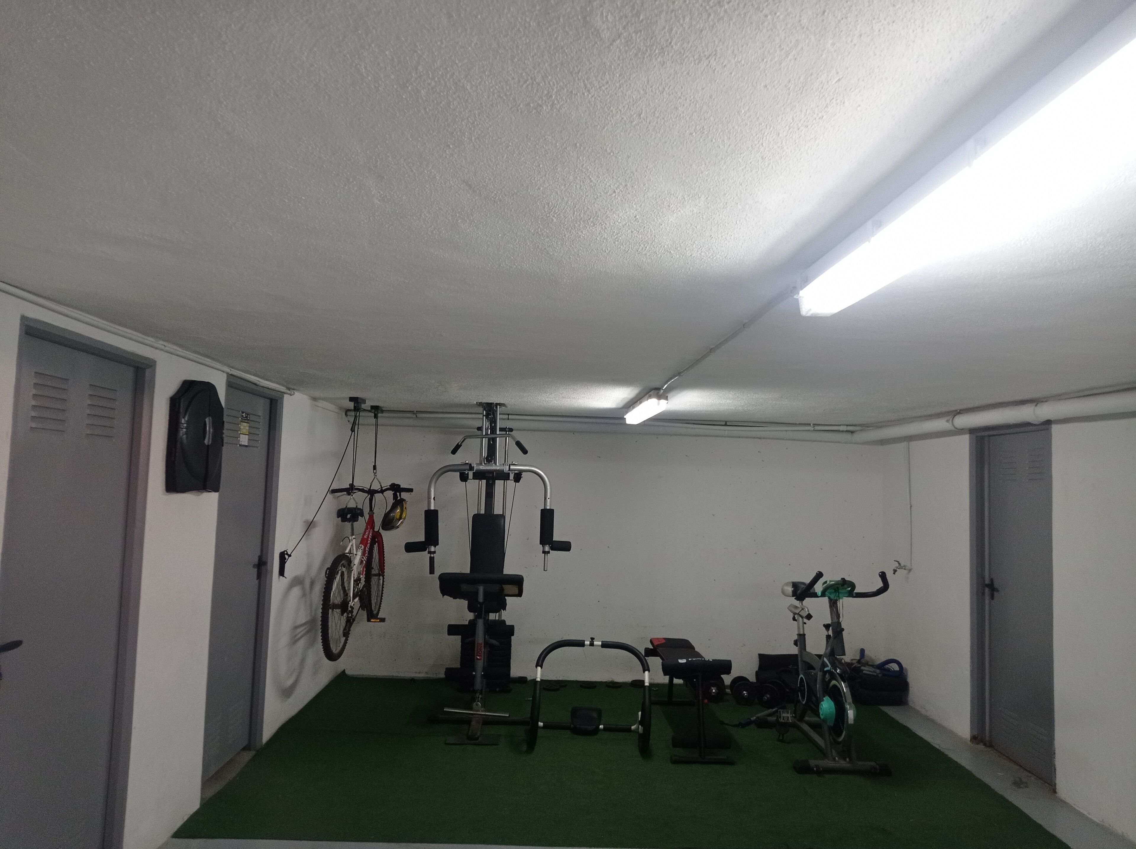 Une salle de sport équipée de matériel d’exercice, d’un vélo et recouverte d’une moquette verte.