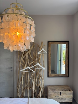 A bedroom with a chandelier, wooden branches, a mirror, and a vintage chest.