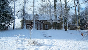 A stone house surrounded by snow-covered trees.
