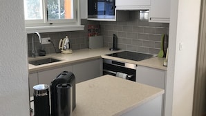 Uma cozinha moderna com micro-ondas embutido, uma pia e uma lava-louças.