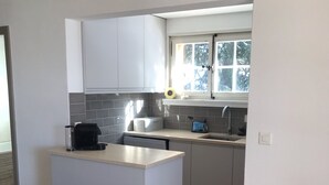 Uma cozinha moderna com armários brancos, uma ilha embutida e uma janela que traz luz natural.