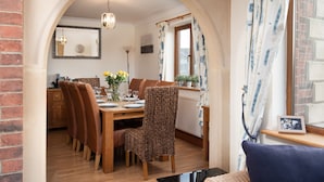 A dining area with a wooden table set for four, surrounded by brown chairs. - Benthall House - sleeps 8 guests  in 4 bedrooms (Beadnell)