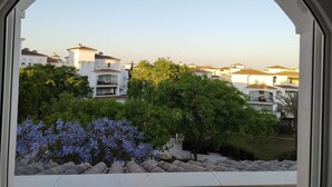 A view through an arched window of a residential area with white buildings and lush greenery. - 2 Bedroom Penthouse Apartment With Large Sun Terrace (Torre-Pacheco)