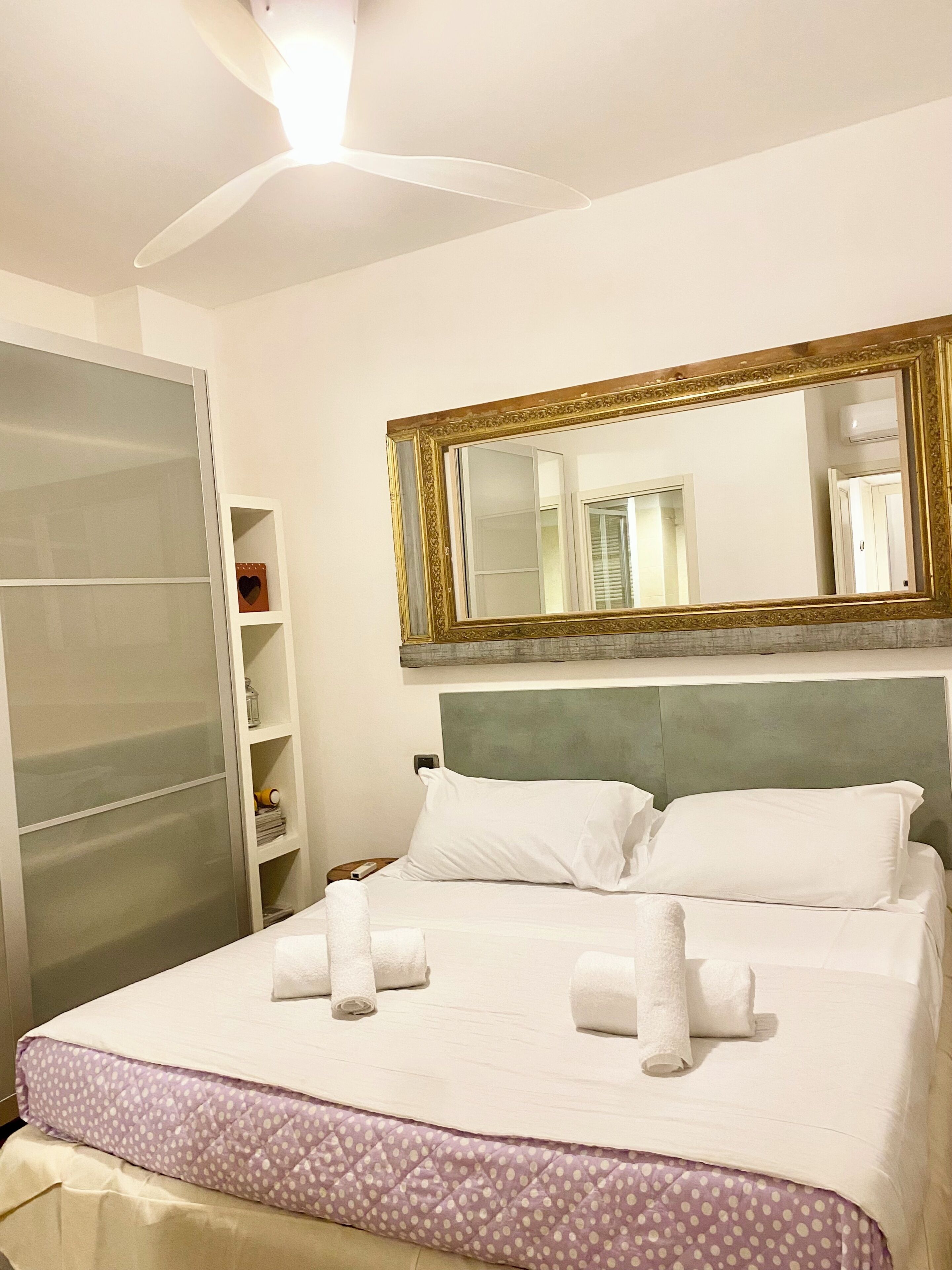 Une chambre d’hôtel avec un lit, un grand miroir, une armoire et une table de chevet.