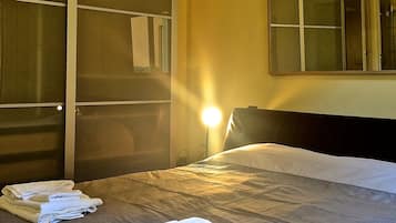 Una camera d'albergo con un letto, un armadio e uno specchio a parete.