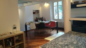 A modern kitchen with wooden flooring, a dining table set for two, and a view of the outdoors through a large window. - Very central, On 2 levels, fully renovated, ideal for families  (Como)