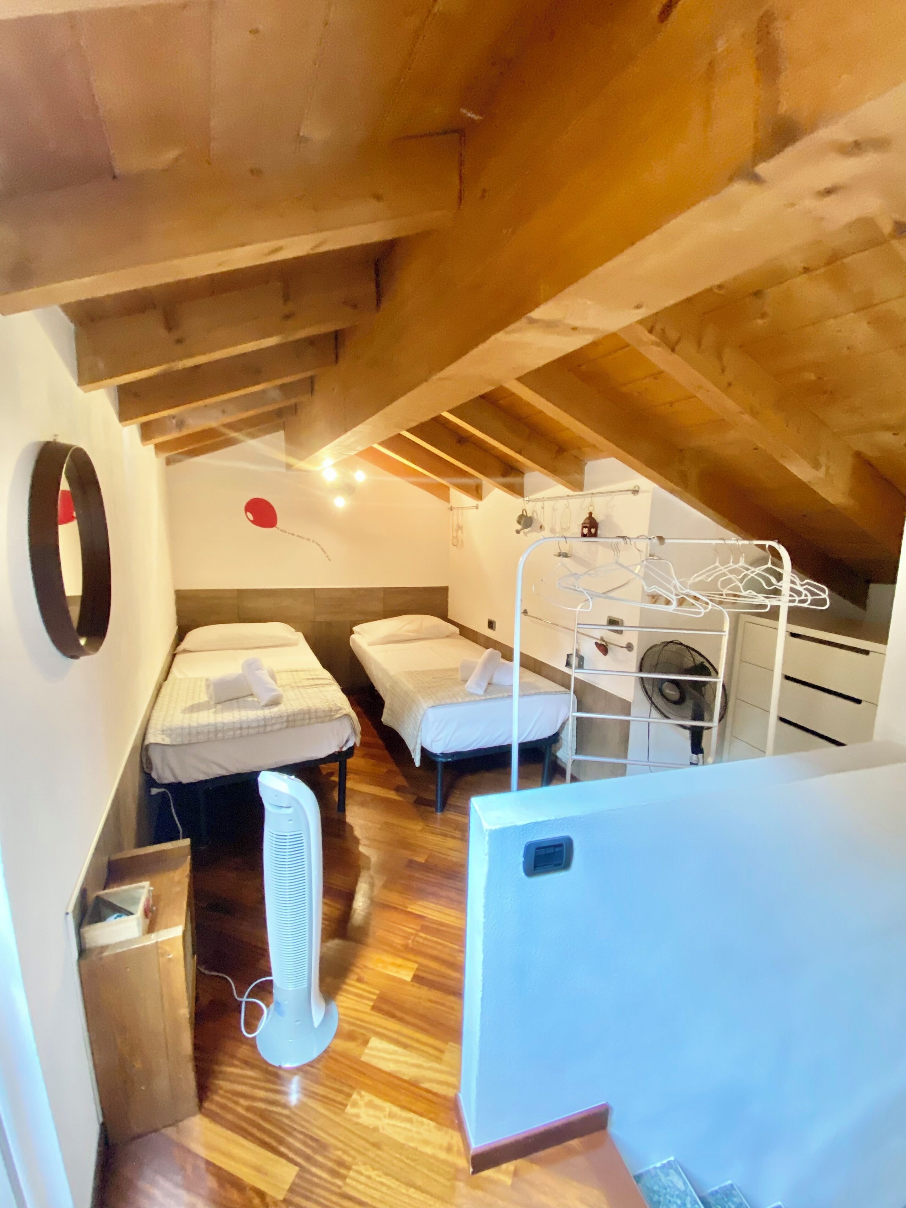 A compact room with two beds, a small heater, and a fan.