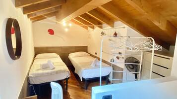 A compact room with two beds, a small heater, and a fan.