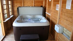 Una cabaña de madera con hidromasaje, un banco y paredes de madera.